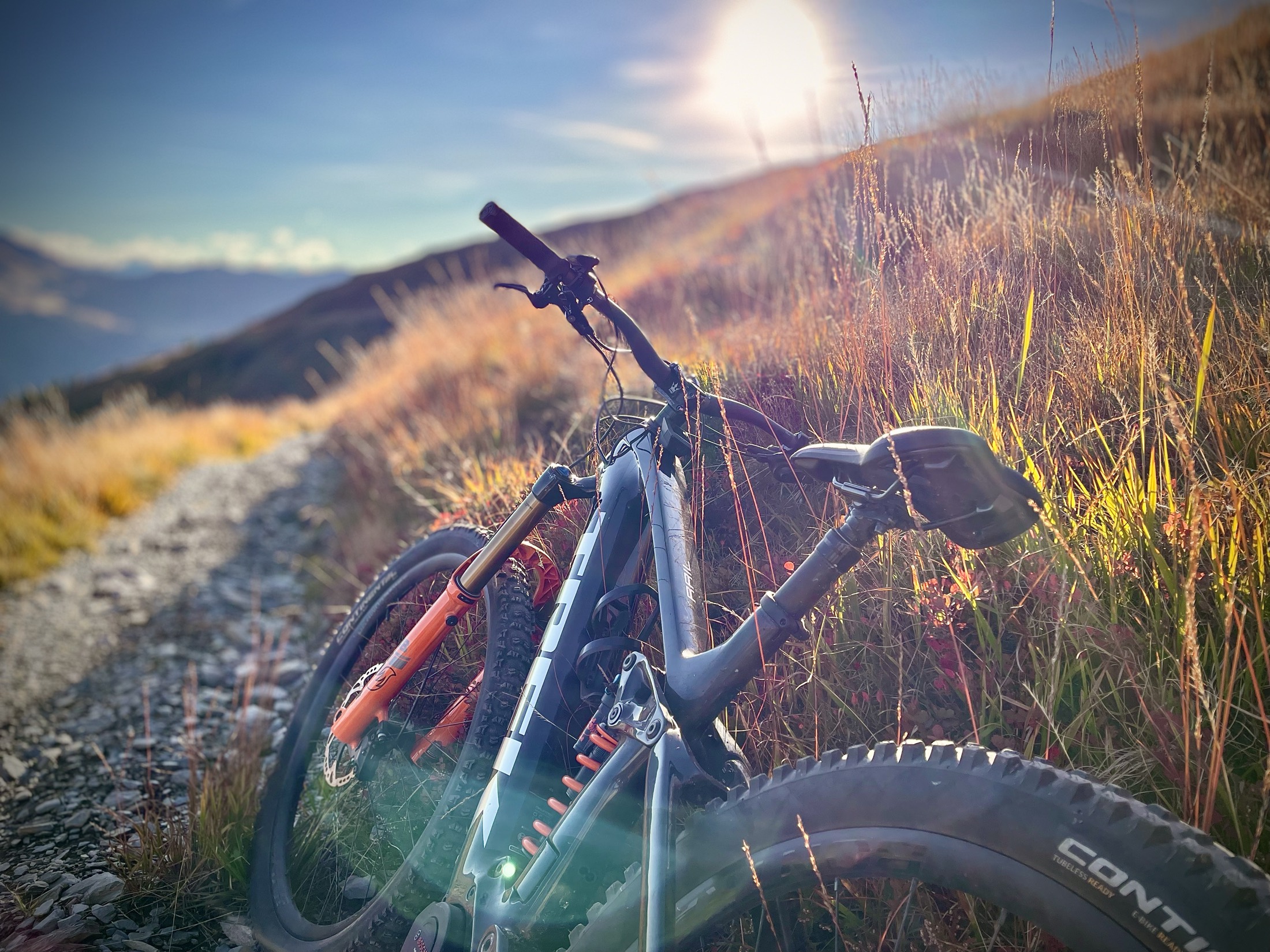 E-MTB auf einem Schotterweg im Abendlicht der Berge